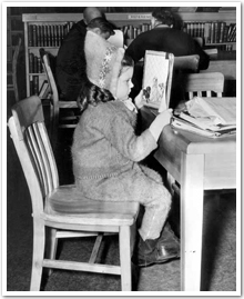 Photo of little girl (Gail Dingle) reading a book in library. Sudbury Public Library, March 8, 1947.