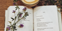 close view of a desk with a paper with lines of poetry next to a coffee cup 