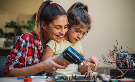 une mère et son enfant travaillent ensemble sur un panneau de circuit imprimé.